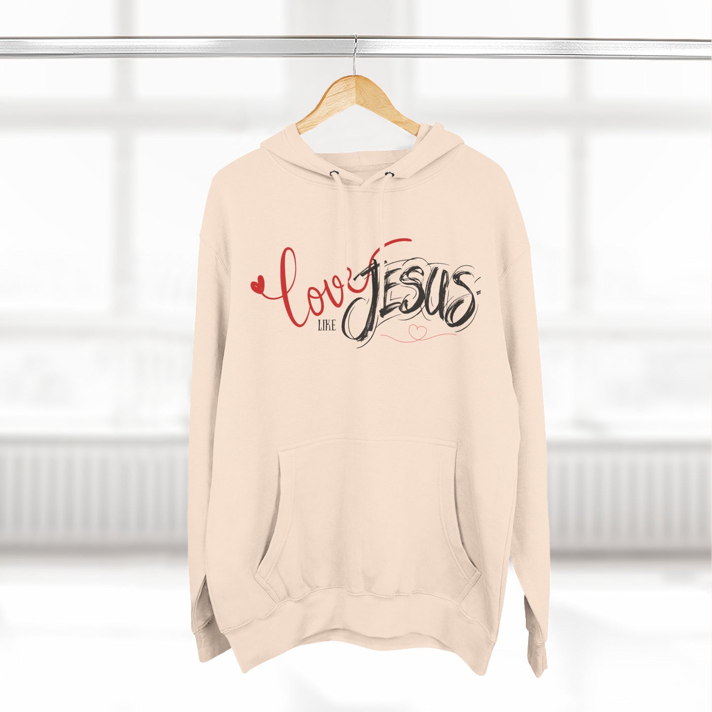 Beige hoodie with 'Love like Jesus' text on a hanger against a white background