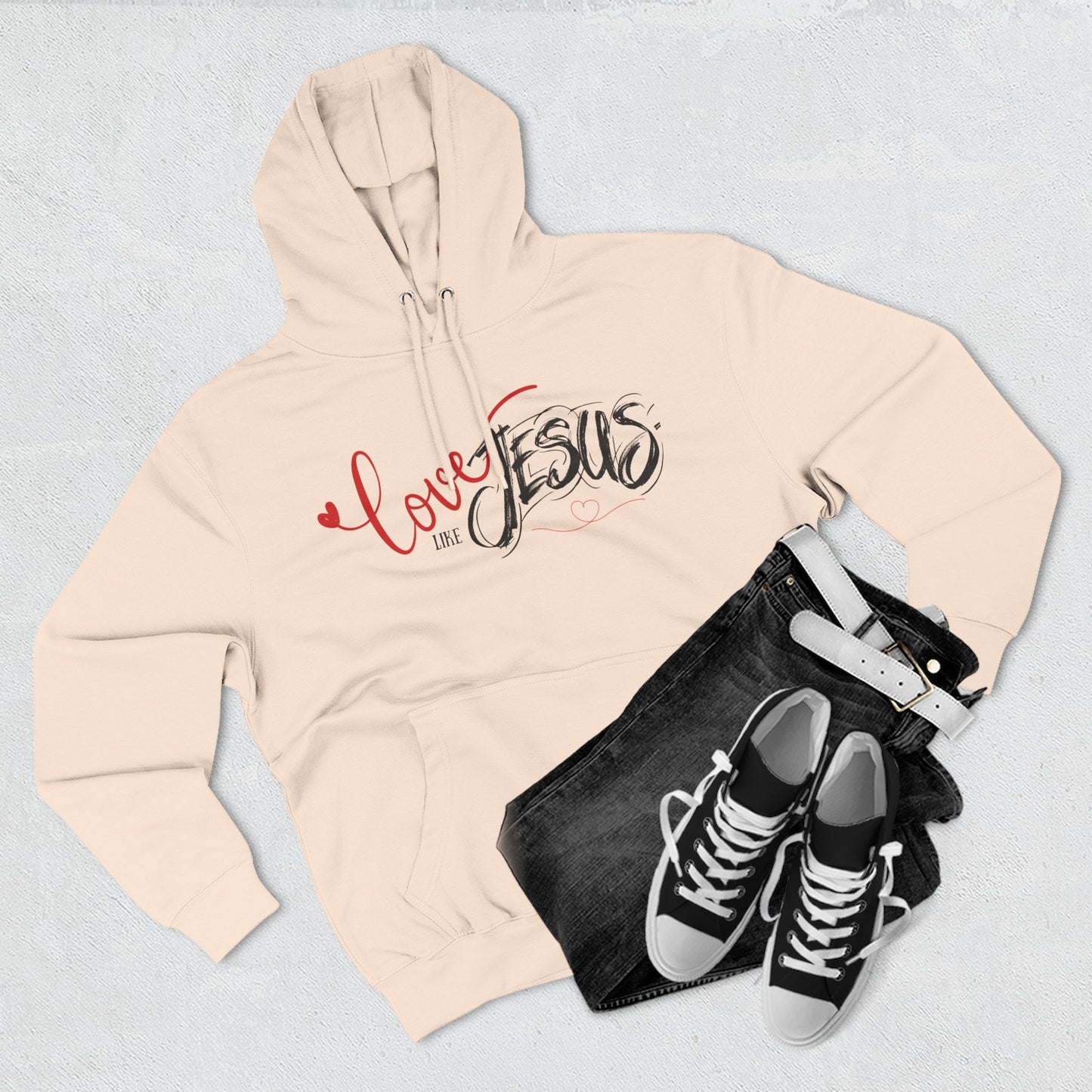 Beige hoodie with 'Love Jesus' text, black shorts, and black sneakers on a light gray background