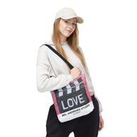 Person holding a tote bag with 'LOVE' and 'Mel Andrews Studio' text on a white background