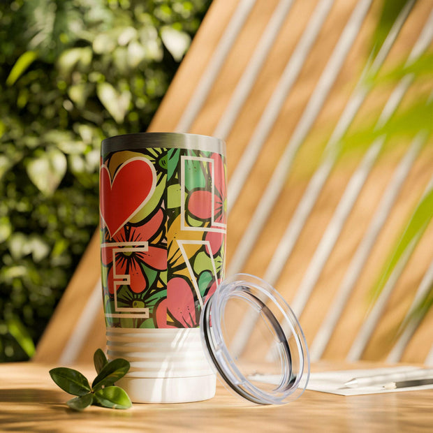 Tumbler with floral design and 'LOVE' text on a wooden surface with plants in the background