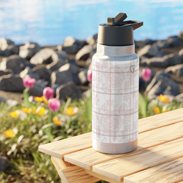 White water bottle with black lid on a wooden surface with flowers and rocks in the background