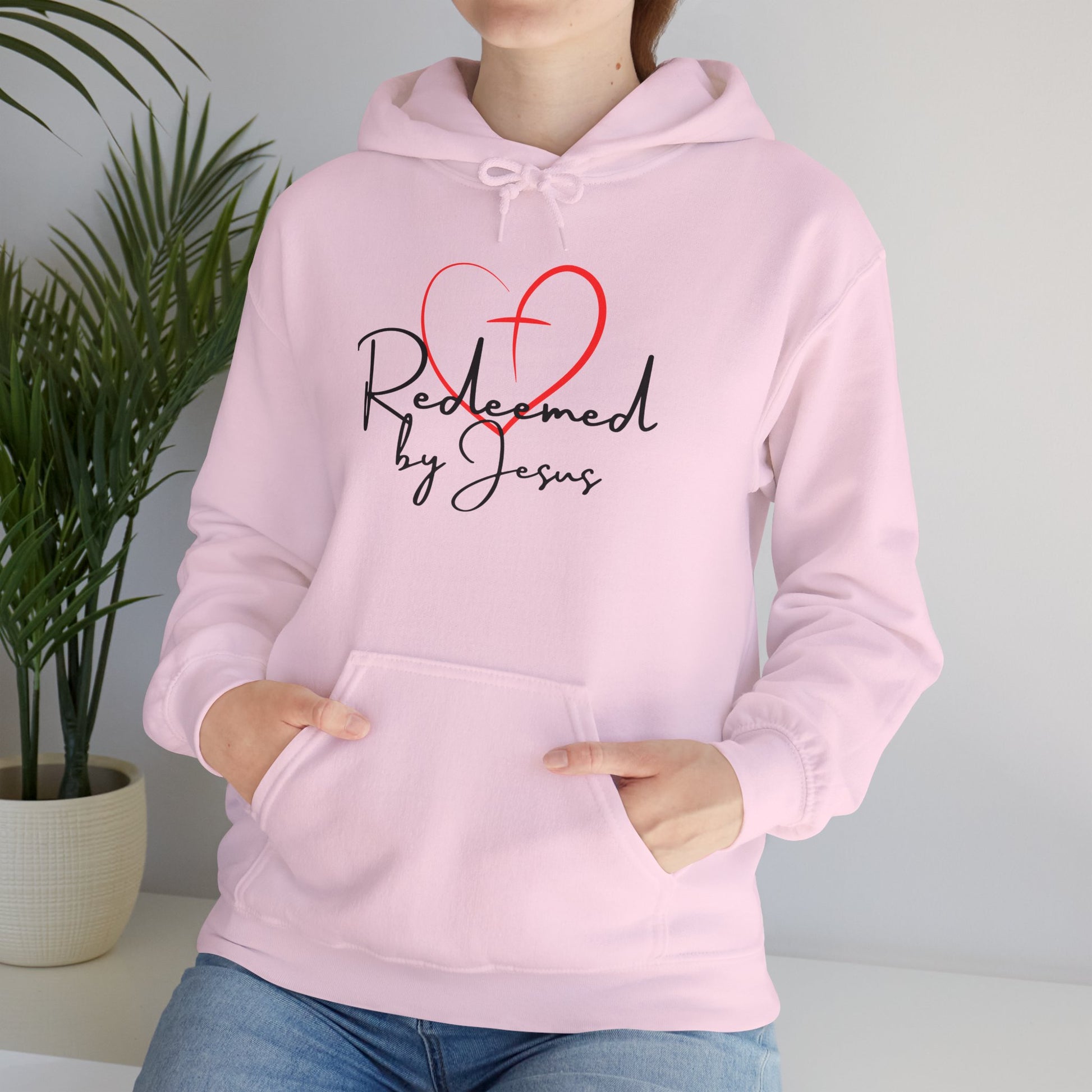 Person wearing a pink hoodie with 'Redeemed by Jesus' text and heart design.