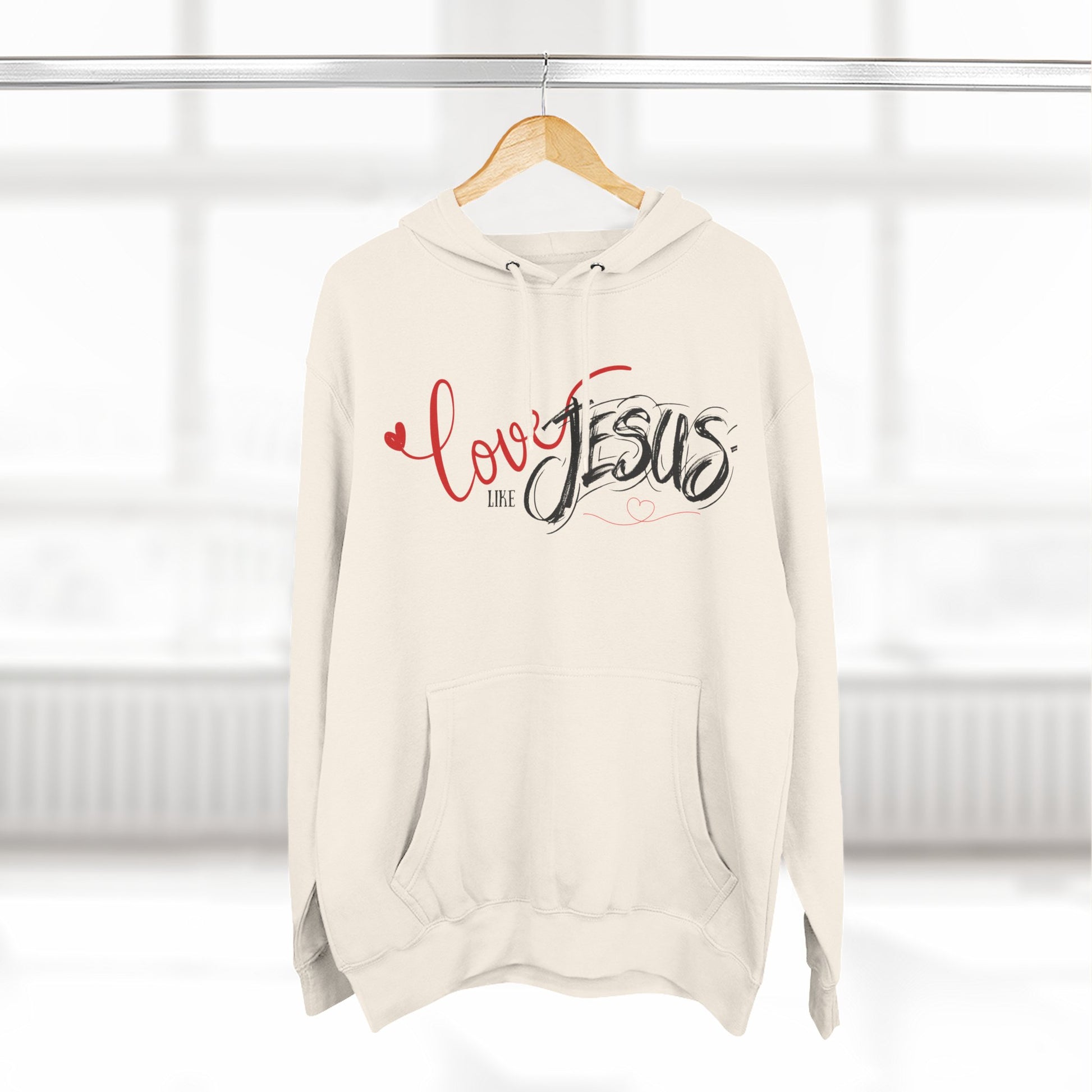 Beige hoodie with 'Love like Jesus' text on a hanger against a white background