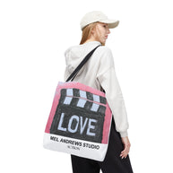 Person wearing a white hoodie and cap, carrying a tote bag with 'Mel Andrews Studio' branding.