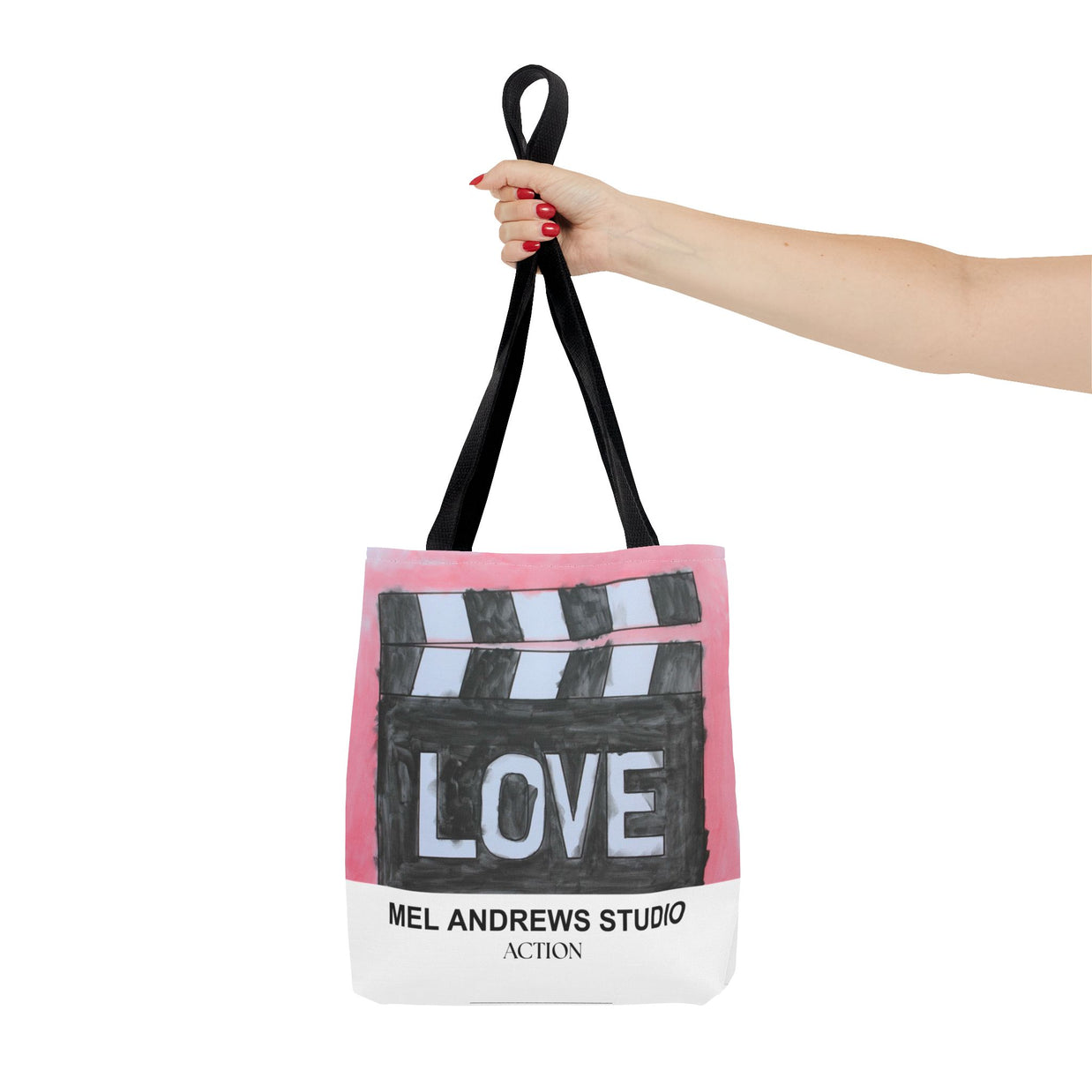 Tote bag with clapperboard design and 'Mel Andrews Studio' text, held by a hand.