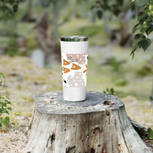 White tumbler with autumn-themed design on a wooden stump outdoors