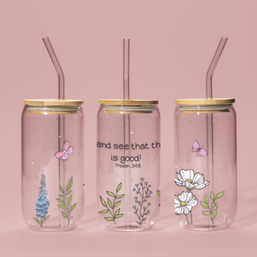 Three clear tumblers showing sides and front with floral designs and gold lids on a pink background