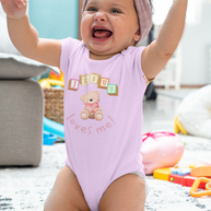 Baby in a pink onesie with teddy bear design and 
