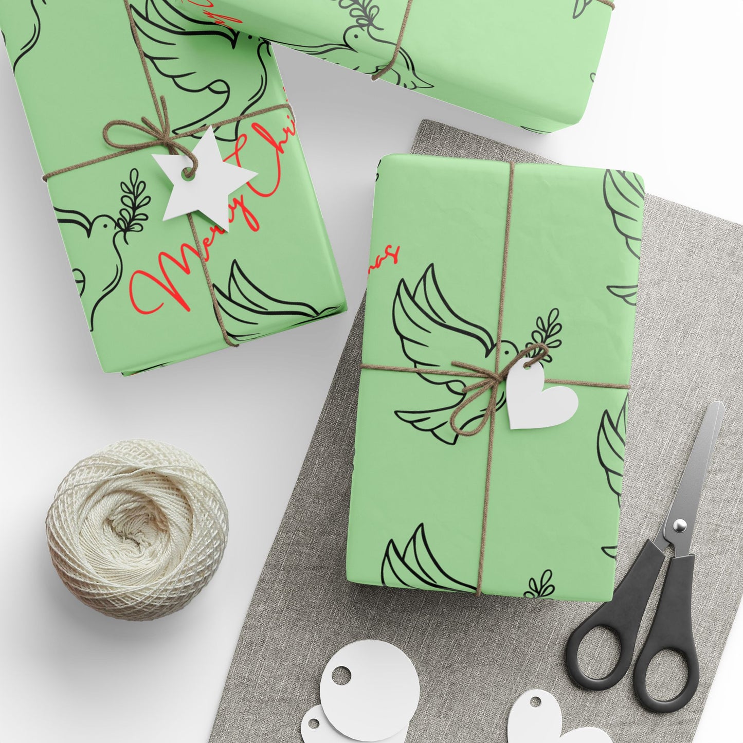 Green gift boxes with decorative ribbons, tags, and scissors on a white surface