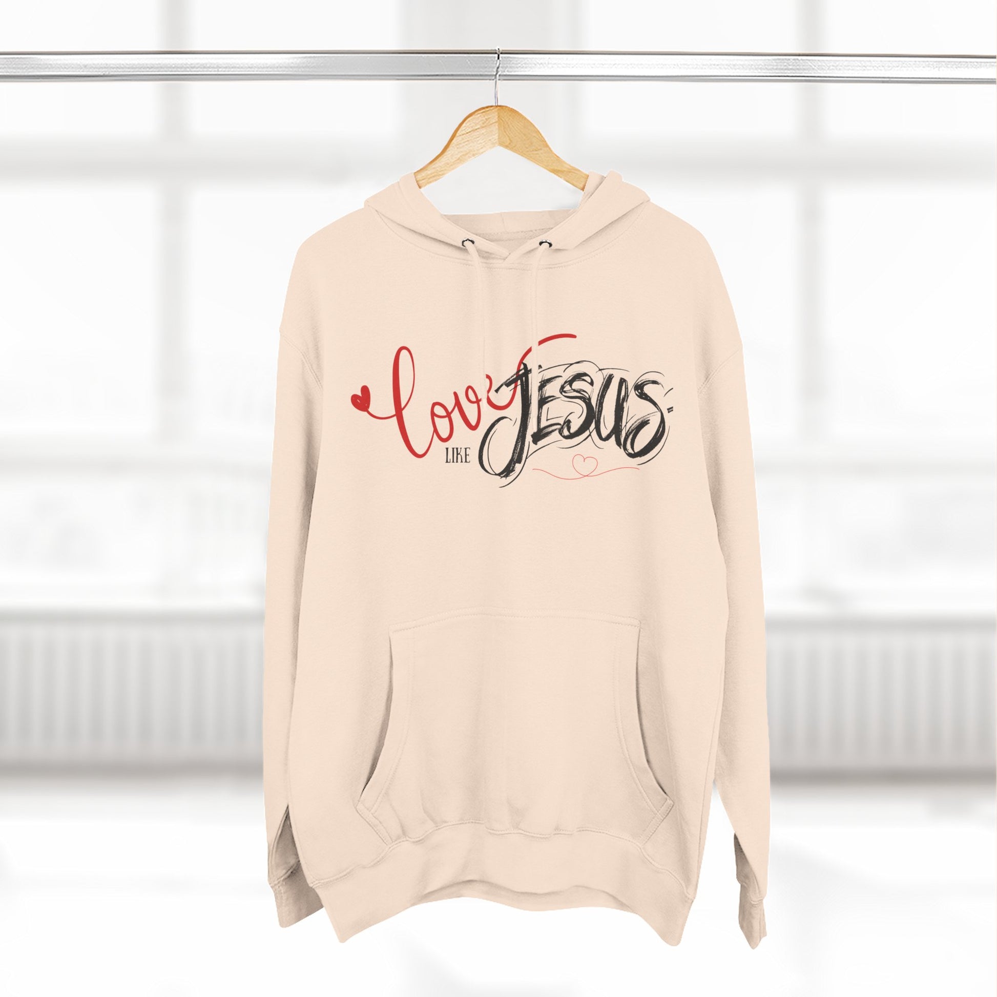 Beige hoodie with 'Love like Jesus' text on a hanger against a white background