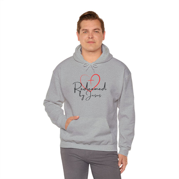 Person wearing a gray hoodie with 'Redeemed by Jesus' text and heart design on a white background