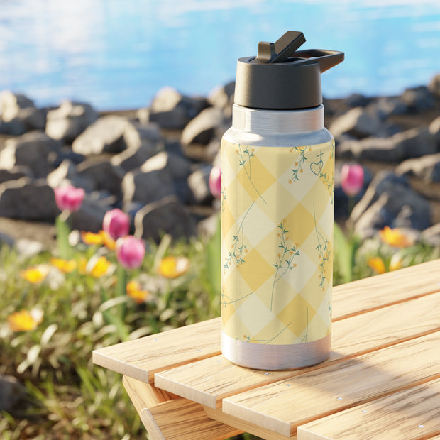 Floral-patterned water bottle on a wooden surface with a scenic background
