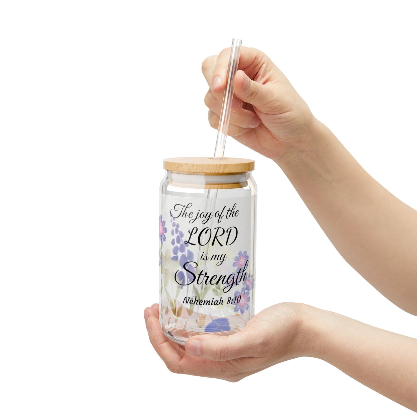 Hand holding a glass tumbler with a wooden lid and straw, featuring a faith-inspiring Bible quote.